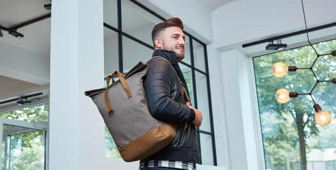 Mann traegt einen zweifarbigen LIFE Notebook-Rucksack in modernem Innenraum.
