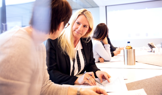 Zwei Mitarbeitende sitzen zusammen an einem Tisch um sich fachlich auszutauschen