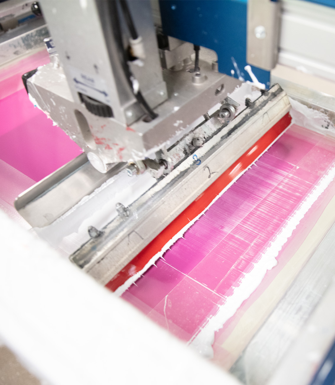Siebdruckmaschine mit pinker Wasserfarbe im Veredelungsprozess