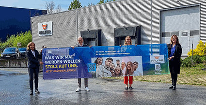 Halfar Team hält IHK Banner zur Ausbildung vor Firmengebäude