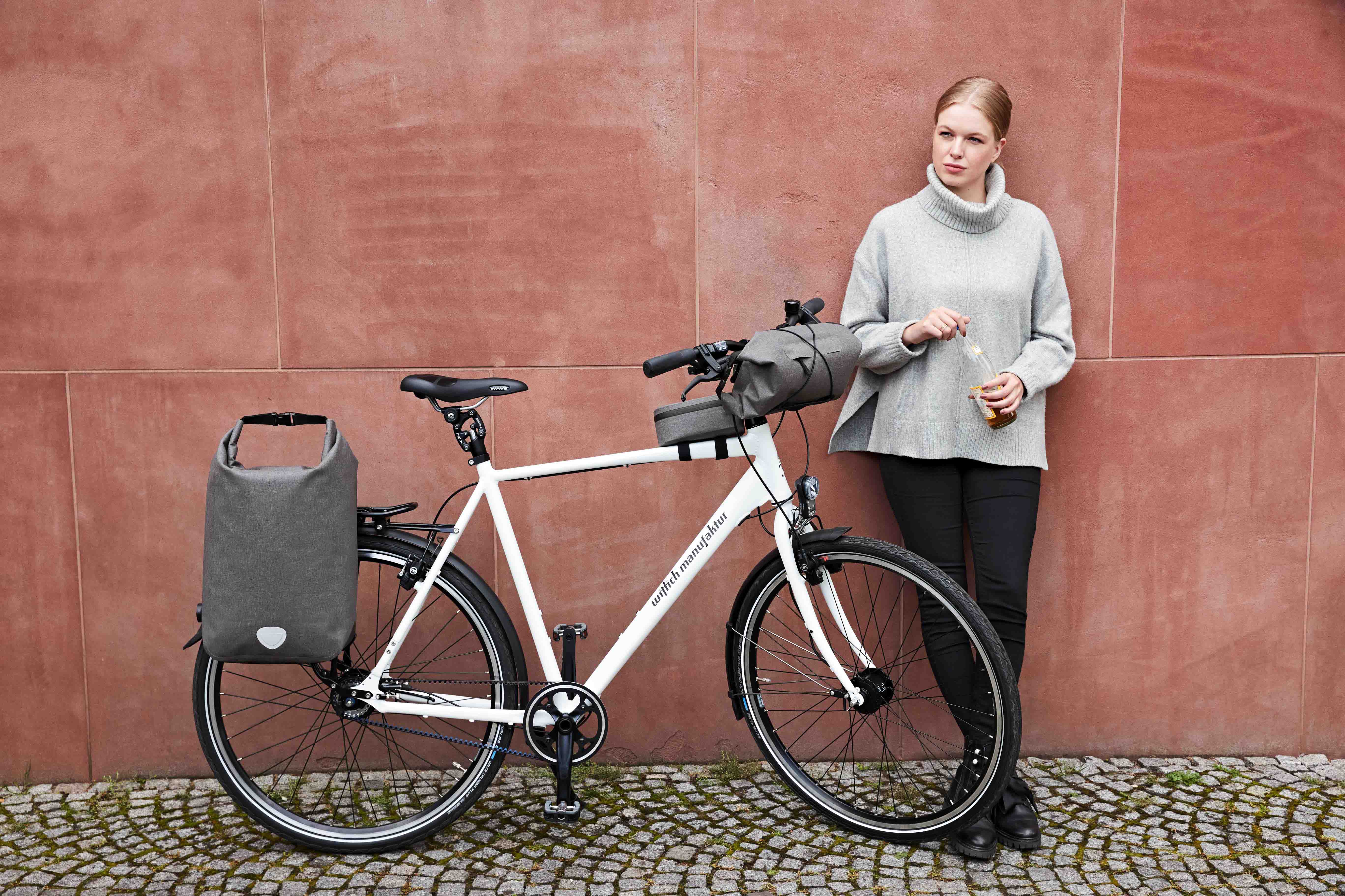 Mehrere graue CYCLE Fahrradtaschen als Serienuebersicht vor einer Wand.