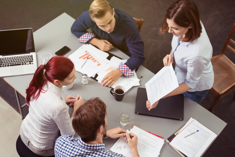 Mitarbeitende sitzen zusammen und besprechen Arbeitsmaterialien