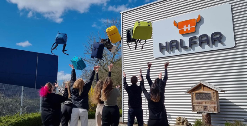 Halfar Azubis werfen Rucksäcke vor Firmengebäude in die Luft