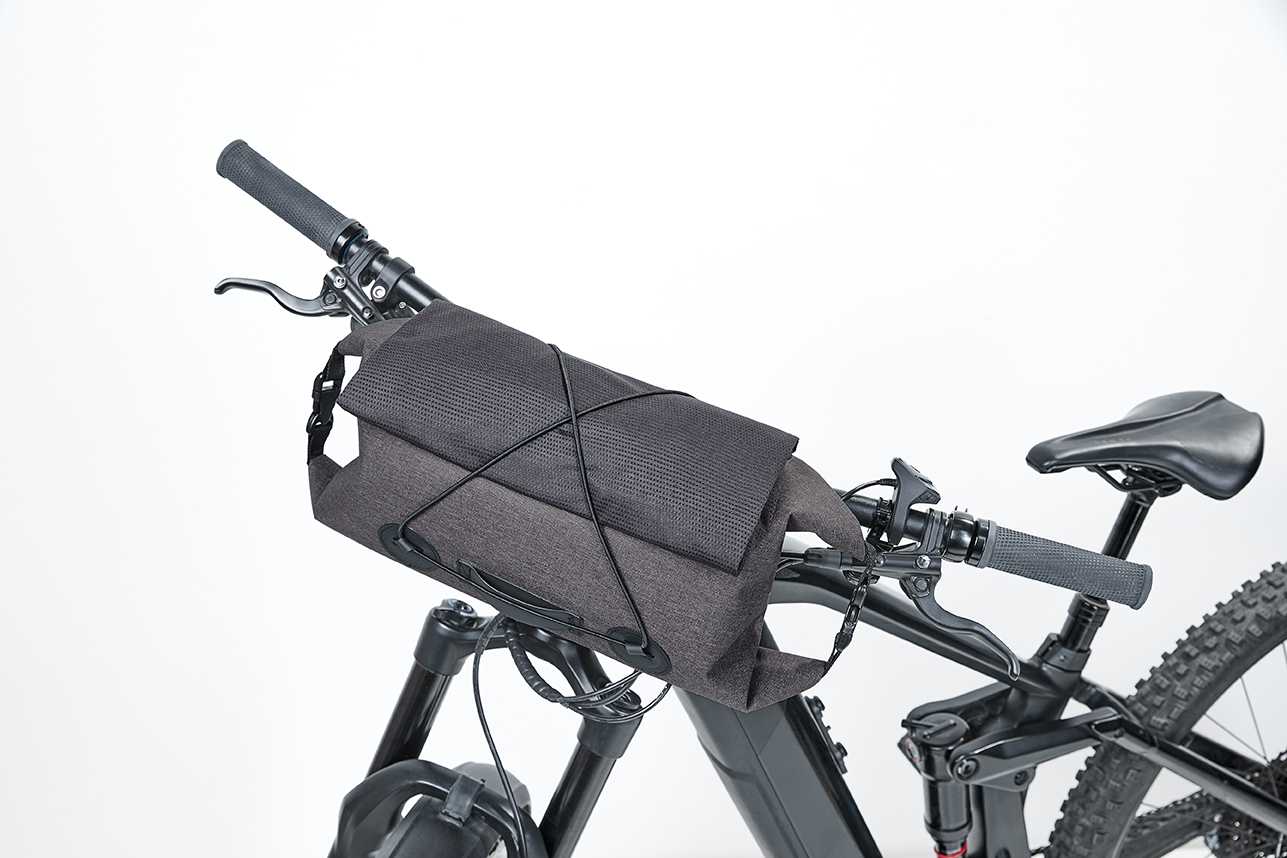 Graue CYCLE Lenkertasche ist direkt am Lenker eines Fahrrads befestigt.
