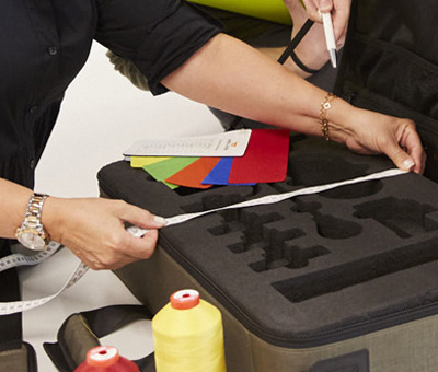 Mitarbeitende misst mit einem Maßband eine maßgefertigte Transporttasche von HALFAR® aus