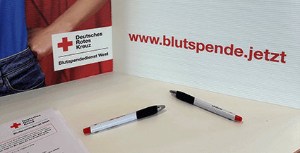 Blutspendeaktion mit DRK Aufsteller und Stiften auf Tisch